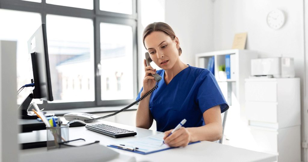 Healthcare professional talking on the phone and taking notes in a medical office while discussing pregnancy care options.