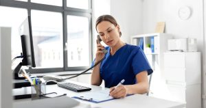 Healthcare professional talking on the phone and taking notes in a medical office while discussing pregnancy care options.